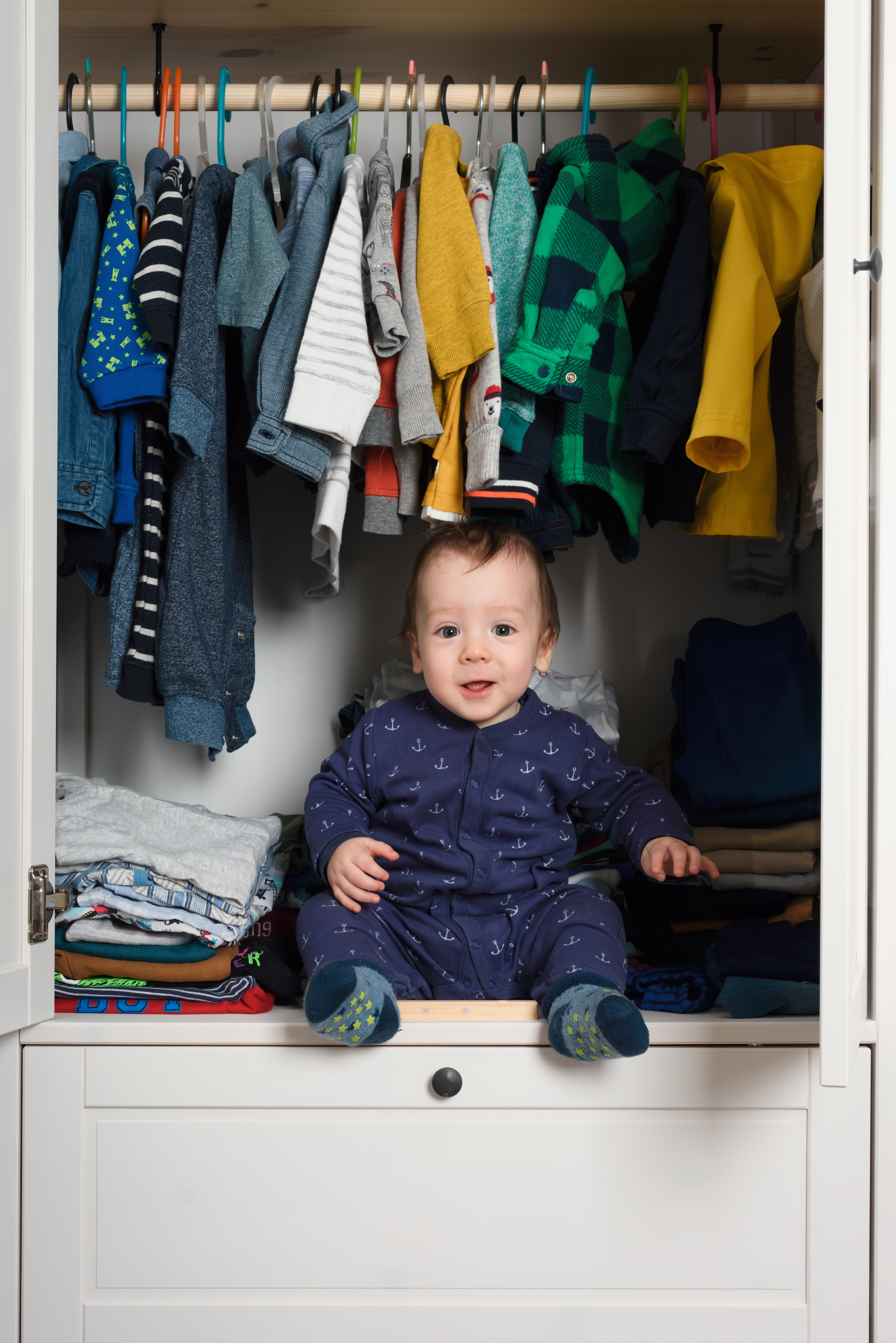 Smiling kid hiden in clothing closet